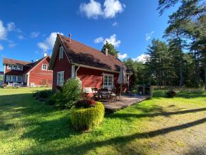 ein rotes Haus mit einer Holzterrasse im Hof in der Unterkunft Villa Hanson in Noarootsi