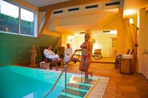 a woman in a bikini standing next to a swimming pool at Wellness Hotel Harms in Bad Nenndorf