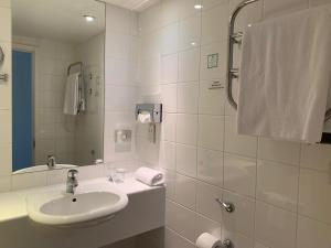 a bathroom with a sink, mirror, towel rack and towel dispenser at Holiday Inn Birmingham City, an IHG Hotel in Birmingham