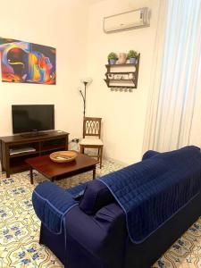 a living room with a blue couch and a tv at Le Esperidi House in Ravello