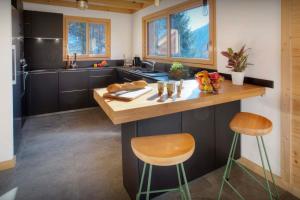 a kitchen with a counter with two stools and a sink at Chalet Elomaz - OVO Network in Saint-Jean-de-Sixt