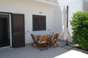 une terrasse avec une table, des chaises et un parasol dans l'établissement Casa Luri, à Porto Cesareo