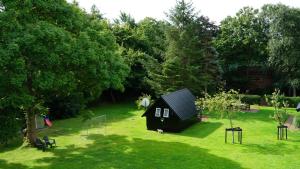 ein kleines schwarzes Haus inmitten eines Gartens in der Unterkunft Ferienhaus Vogelkoje in Emmelsbüll-Horsbüll