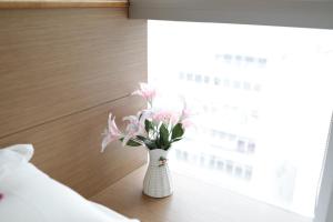 um vaso com flores cor-de-rosa sentado numa mesa ao lado de uma janela em O' Hotel em Hong Kong