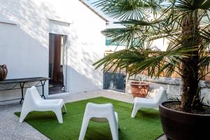 a patio with three white chairs and a table and a palm tree at L'Appart in Ruelle-sur-Touvre