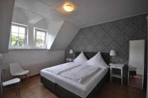 a bedroom with a large white bed and two windows at Apartments / Ferienwohnungen Moseluferstrasse in Neef