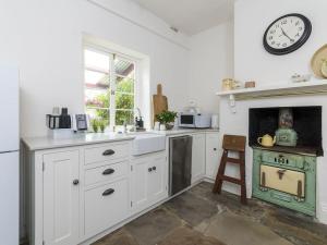 a kitchen with a stove and a clock on the wall at Fig Tree Cottage in Angaston