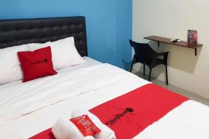 una camera con letto con cuscino rosso e scrivania di RedDoorz at Mayjen Sungkono Surabaya a Surabaya