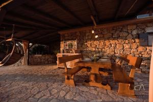 a wooden table and bench in front of a stone wall at Heritage Stonehouse Jure in Krk