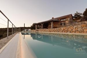 a swimming pool with a stone wall and a house at Heritage Stonehouse Jure in Krk