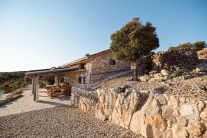 a stone house on a hill with a stone wall at Heritage Stonehouse Jure in Krk
