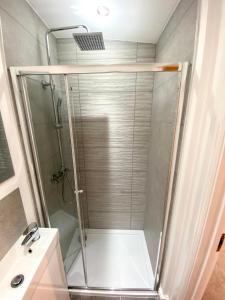 a shower with a glass door next to a sink at Blackberry Cottage in Sutton Valence