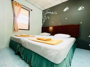 a bedroom with two beds with white sheets and birds on the wall at Phang Nga Guesthouse in Phangnga