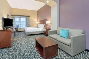 a hotel room with a couch and a bed and a television at La Quinta by Wyndham Oklahoma City -Yukon in Yukon