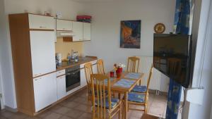 une cuisine avec des armoires blanches et une table et des chaises dans l'établissement Wellenberg, à Breege