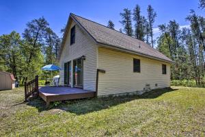 Secluded Irons Cabin with 5-Acre Yard, Deck, Grill! في Irons: منزل أصفر صغير مع شرفة في الفناء