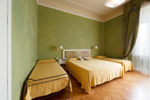 a green room with two beds and a window at Hotel Gennarino in Livorno