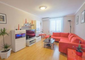 salon z czerwoną kanapą i telewizorem w obiekcie Apartman Andja sea and garden view w mieście Peroj