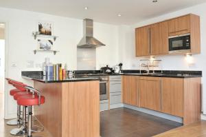 a kitchen with wooden cabinets and black counter tops at Perfectly Located Beautiful Ensuite and Gym in London