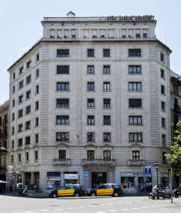 a bus is parked in front of a tall building at Fisa Rentals Gran Via Apartments in Barcelona