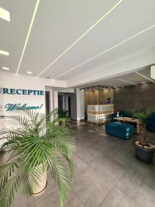 un vestíbulo de oficina con un sofá azul y plantas en Turquoise Boutique, en Mamaia Nord – Năvodari