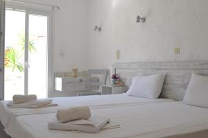 a white bedroom with a large bed with towels on it at Xenios Dias in Matala