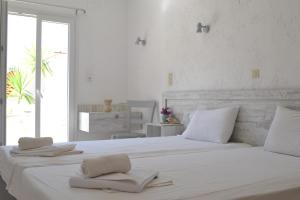 una camera bianca con un grande letto con asciugamani di Xenios Dias a Mátala