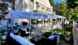 een restaurant met een blauwe parasol en tafels en stoelen bij Majestique in Pobierowo