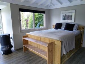 a bedroom with a wooden bed and a window at Tuinverblijf Lauwersmeer in Anjum