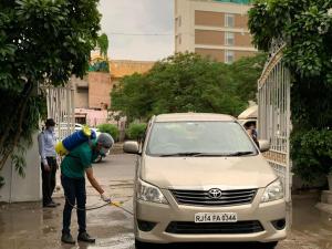 a man is washing a car with a hose at Devraj Niwas in Jaipur