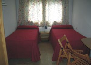1 Schlafzimmer mit 2 Betten, einem Stuhl und einem Fenster in der Unterkunft Aparthotel Condor in Pas de la Casa