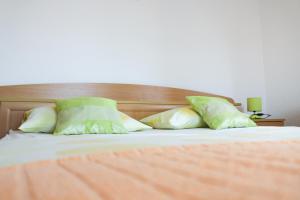 a bed with two green pillows and a wooden headboard at Apartments Marušić in Vinišće