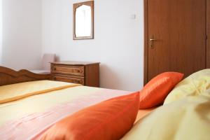 1 dormitorio con 1 cama con almohadas de color naranja y espejo en Apartments Marušić, en Vinišće
