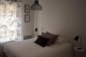 sypialnia z białym łóżkiem z poduszkami i oknem w obiekcie Burdigala Homes - Appart de Lalande w mieście Bordeaux