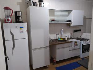 a kitchen with a white refrigerator and a sink at Apartamento na Praia da Enseada in Guarujá