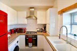 a kitchen with white cabinets and a red refrigerator at Guest Homes - Cambrian Apartment in Swansea