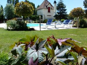 a garden with a pool and chairs and a house at Camping Au Clos de Beaulieu in Bossée
