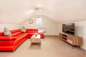 a living room with a red couch and a flat screen tv at Guest Homes - Carriage Court in Worcester