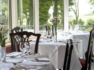 uma mesa de jantar com toalhas de mesa brancas e copos de vinho em Carrygerry Country House em Shannon