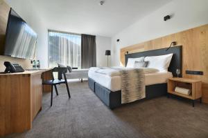 a hotel room with a large bed and a desk at Grand Hotel Hradec in Pec pod Sněžkou