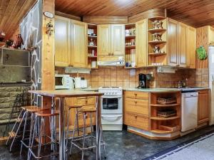 una cucina con armadi in legno e bancone con sgabelli di Holiday Home Sakumaja by Interhome a Levi