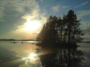um pôr-do-sol sobre um lago com árvores na água em Holiday Home Tipuniemi by Interhome em Vähä Evo