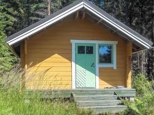 una piccola casa gialla con porta verde e scale di Holiday Home Pikku harrila by Interhome a Huuhanaho