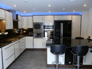 a kitchen with white cabinets and black appliances at Castle House Holiday Home in Chapel en le Frith