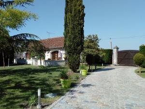 uma casa com uma árvore e uma entrada de tijolos em Chambres d'hôtes Au Clos de Beaulieu em Bossée