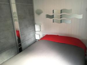 a small bedroom with a red bed and a mirror at Chalet orange naturiste la Jenny in Le Porge