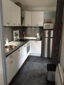 a kitchen with white cabinets and a stainless steel refrigerator at Chalet orange naturiste la Jenny in Le Porge