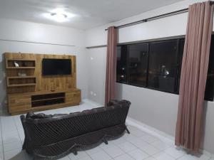 a living room with a couch and a television at Apartamento na Praia da Enseada in Guarujá