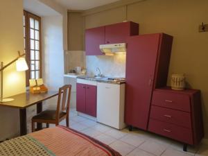eine Küche mit lila Schränken, einem Tisch und einem Schreibtisch in der Unterkunft Au Figuier des Cévennes in Saint-Germain-de-Calberte