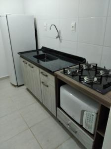 eine Küche mit einem Herd, einer Spüle und einem Kühlschrank in der Unterkunft AP Confortável San Inácio in Santo Ângelo